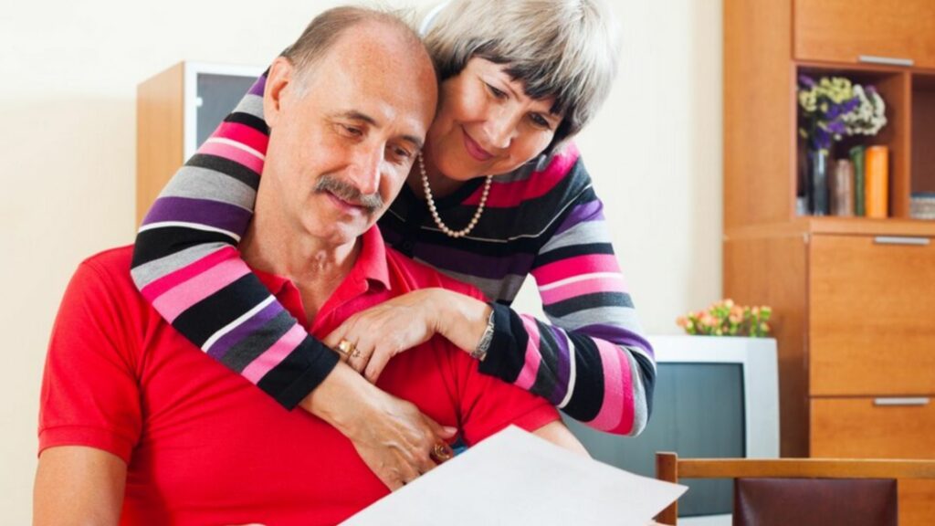 Retirement Benefit Reduction and Age: a man holding a white paper with his wife hugging him 